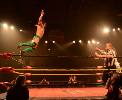 PAC leaps off the top rope towards Brodie Lee